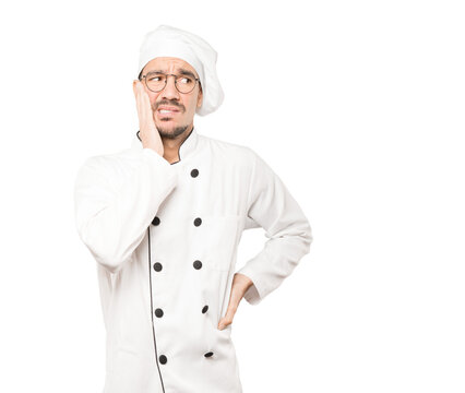 Concerned young chef posing against background