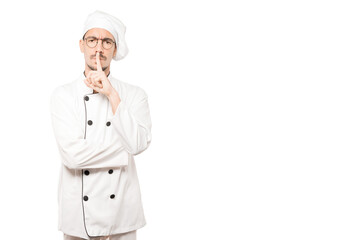 Serious young chef asking for silence gesturing with his finger