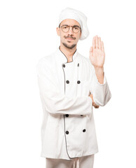 Serious young chef making a gesture of stop with his palm