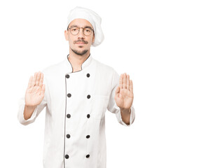 Serious young chef making a gesture of stop with his palm