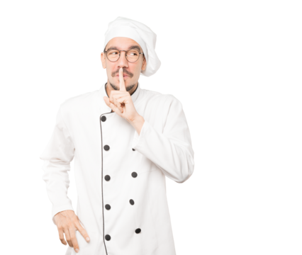 Amazed young chef asking for silence gesturing with his finger