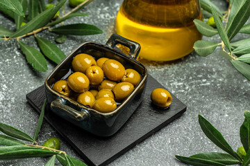 Branch with olives and a bottle of olive oil on dark background. top view. place for text