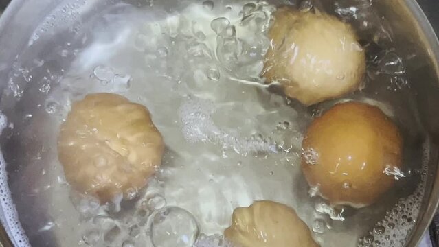 Chicken eggs are cooked in boiling water in a saucepan.