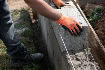 Bricklayer in glove spreading concrete to build a wall on construction site