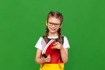Education in Germany for children. A little girl with a German flag and notebooks on a green isolated background. Learning foreign languages.