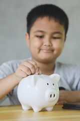 Asian boy happy Putting Coin In Piggy Bank. saving money concept.