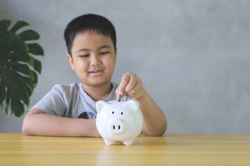 Asian boy happy Putting Coin In Piggy Bank. saving money concept.