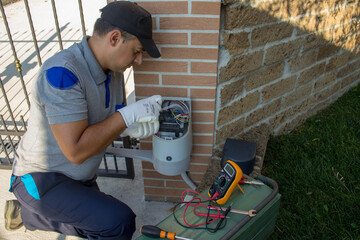 Electrician repairing the motor and electrical part of a driveway gate. Do it yourself work
