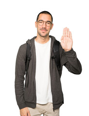 Happy student making a gesture of stop with his palm