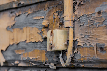 An old light switch on a wooden wall with peeling paint. Selective focus. An old switch on the wall in close-up.