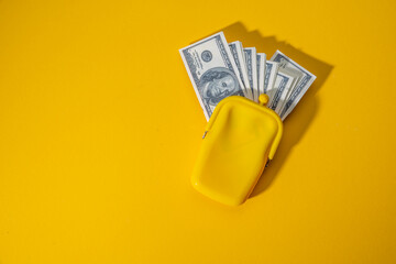 Yellow wallet with 100 dollar bills. Top view of cash. The concept of finance, payment, earnings. Lemon color background - obrazy, fototapety, plakaty