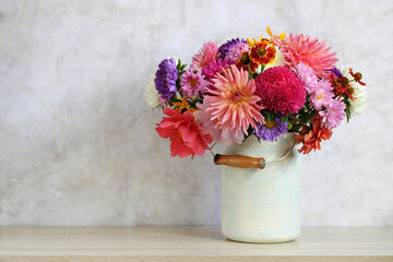 Autumn bouquet in a can on the table in a bright interior. Chrysanthemums, asters and dahlias.