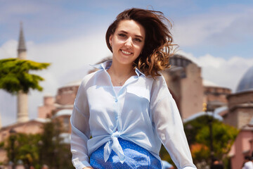 Fototapeta premium European girl in a blue skirt on the background of a mosque. photo session of a girl on the background of hagia sophia in istanbul. photo of a tourist in istanbul against the backdrop of attractions