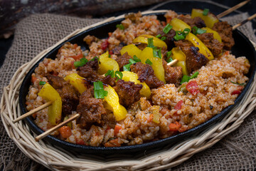 Seitan and bell pepper kebabs with rice pilaf served in cast iron dish