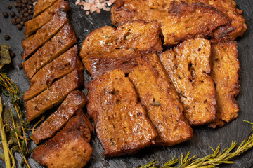 Roasted seitan steaks with herbs and spices on slate plate