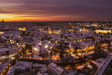 Naklejka premium Beautiful Vilnius city panorama in winter with snow covered houses, churches and streets. Aerial evening view. Winter city scenery in Lithuania.