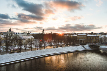 Fototapeta premium Beautiful Vilnius city panorama in winter with snow covered houses, churches and streets. Aerial evening view. Winter city scenery in Lithuania.