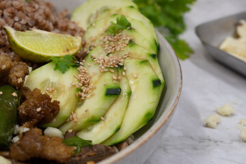 Vegan seitan stir fry bowl with buckwheat, mushroom, pepper and cucumbers