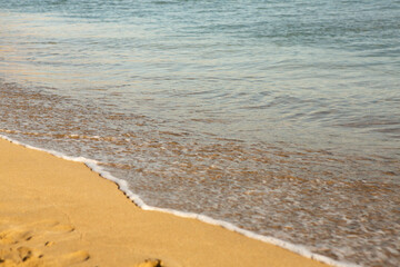 Background with golden sand on the coast of the island of Crete. Abstract surface with sand and clear sea water for text.