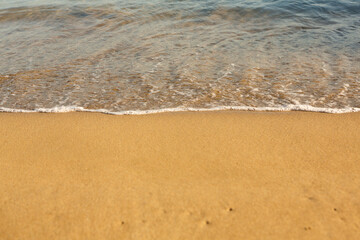 Background with golden sand on the coast of the island of Crete. Abstract surface with sand and clear sea water for text.