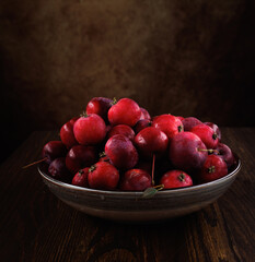 Full plate of fresh red apples on a wooden table. Side view.