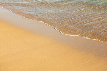 Background with golden sand on the coast of the island of Crete. Abstract surface with sand and clear sea water for text.