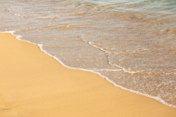 Background with golden sand on the coast of the island of Crete. Abstract surface with sand and clear sea water for text.