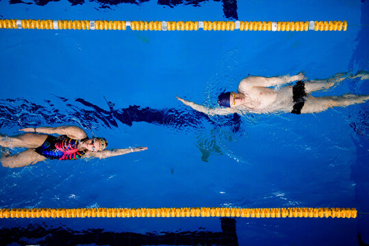 Training of professional swimmers. Athletes swim on their backs in the pool.