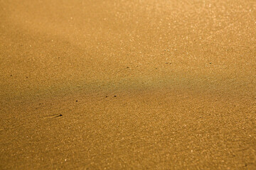 Background with golden sand on the coast of the island of Crete. Abstract surface with sand and clear sea water for text.