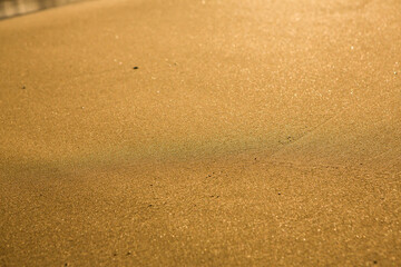 Background with golden sand on the coast of the island of Crete. Abstract surface with sand and clear sea water for text.