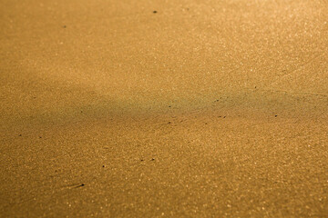 Background with golden sand on the coast of the island of Crete. Abstract surface with sand and clear sea water for text.