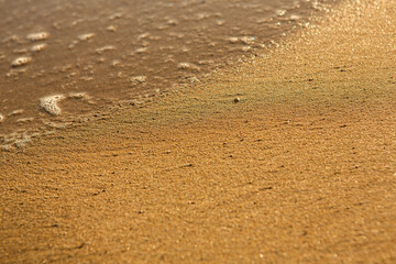 Background with golden sand on the coast of the island of Crete. Abstract surface with sand and clear sea water for text.