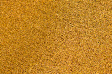 Background with golden sand on the coast of the island of Crete. Abstract surface with sand and clear sea water for text.