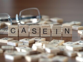 casein word or concept represented by wooden letter tiles on a wooden table with glasses and a book