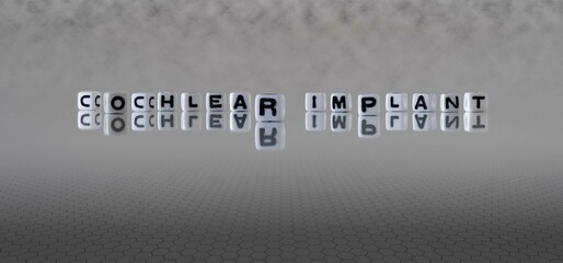 cochlear implant word or concept represented by black and white letter cubes on a grey horizon background stretching to infinity