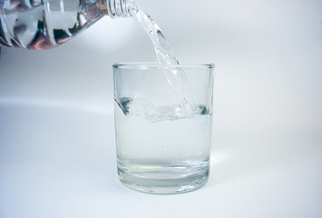 Pouring water into a glass on a white background