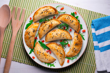 Argentine empanadas handmade with traditional recipe. Aerial shot decorated with red pepper and arugula.