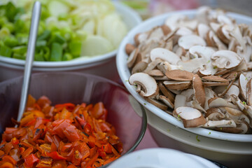 Sliced vegetables like mushrooms, roasted bell peppers and spring onions, fresh ingredients for a healthy vegetarian meal for many people, copy space, selected focus