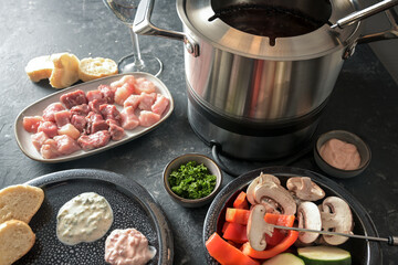 Oil fondue with meat and vegetables to be fried in a pot with hot fat, festive dinner often served...