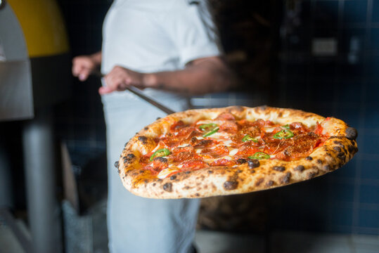 Pizzaiolo holding  pizza