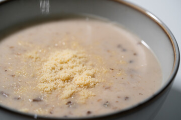 Close up of Homemade mushroom soup with parmeson cheese topping in stoneware bowl isolated on white background.