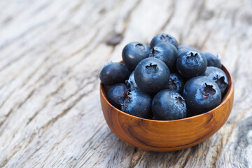Blueberries in wooden bowls on old wooden table background