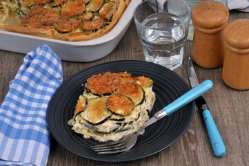 Assiette de gratin de courgettes servie avec un verre d'eau