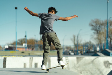 Latin skater boy doing trick in profile at the skate park