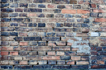 Dirty red grunge brick wall, peeling plaster, grungy texture of darkened brick.