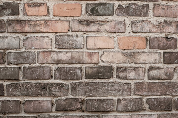 Faded old red brick wall, wide rough vintage texture. Dirty wall with grunge rectangular blocks, close-up, grungy texture of blackened bricks