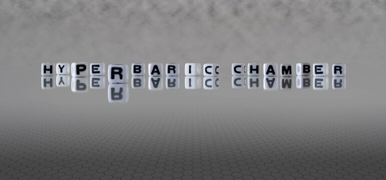 hyperbaric chamber word or concept represented by black and white letter cubes on a grey horizon background stretching to infinity