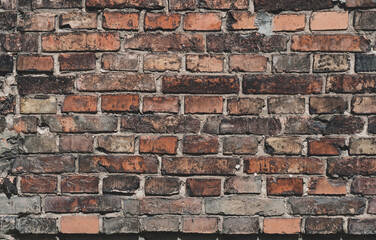 Faded old red brick wall, wide rough vintage panoramic texture. Dirty wall with grunge rectangular blocks, close-up, grungy texture of blackened bricks.