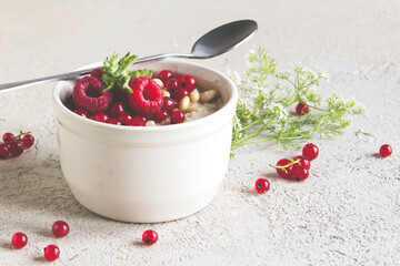 a bowl of oatmeal with berries and nuts on a light table