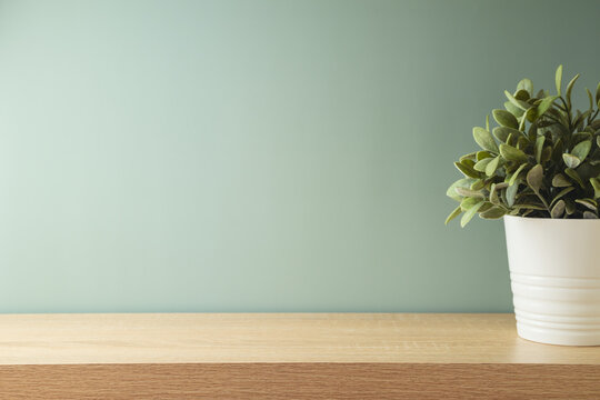 Empty wooden table with home plant decor over green wall background.  Modern interior mock up for design and product display.